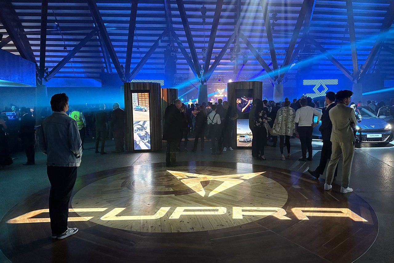 Cupra logo projected on the floor beneath blue beams at the Canberra launch.