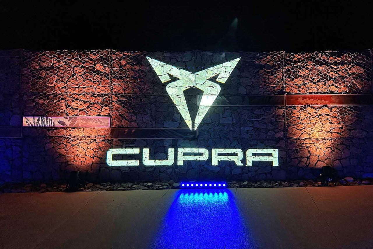 Illuminated Cupra logo on a textured wall at the launch event.