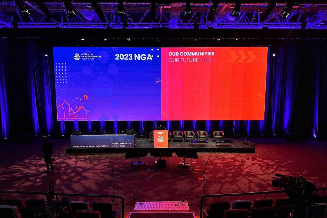 Front view of the podium and wide blue and red screen at the 2023 NGA conference.