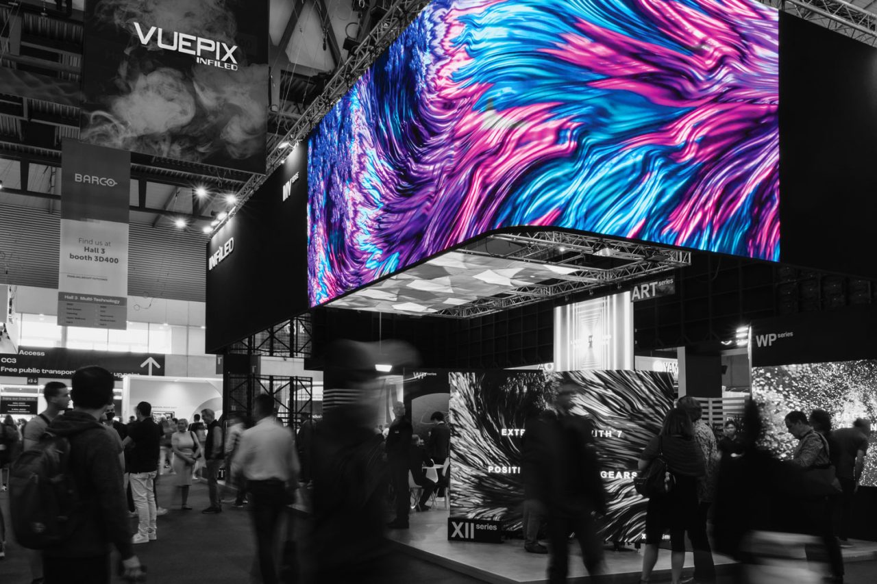 Wide view of the curved Infiled exhibition screen and visitors beneath it.