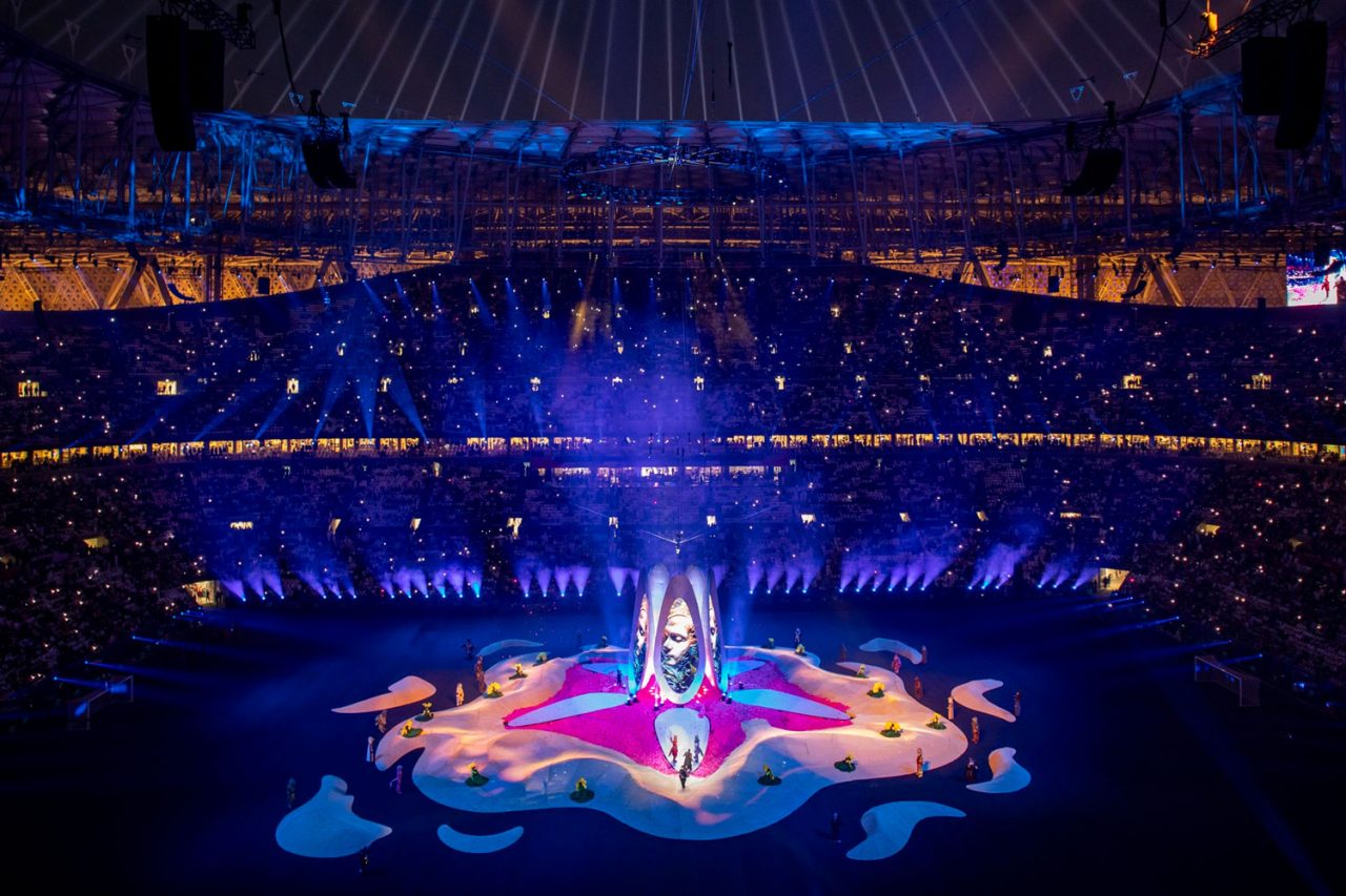 Blue and purple projections surrounding a floral central stage at the Asian Cup opening ceremony.