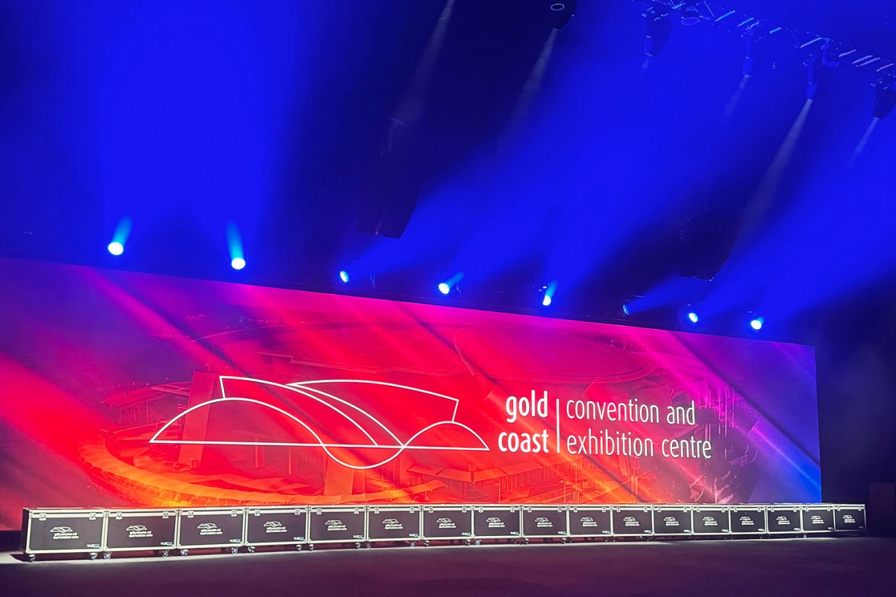 Gold Coast Convention and Exhibition Centre branding on a wide red video wall beneath blue lighting.
