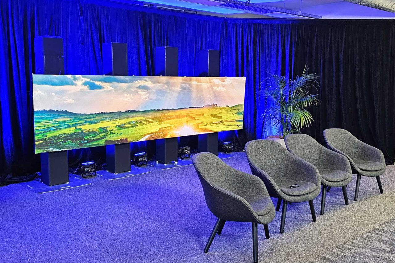 Event seating facing a panoramic landscape display framed by blue curtains.