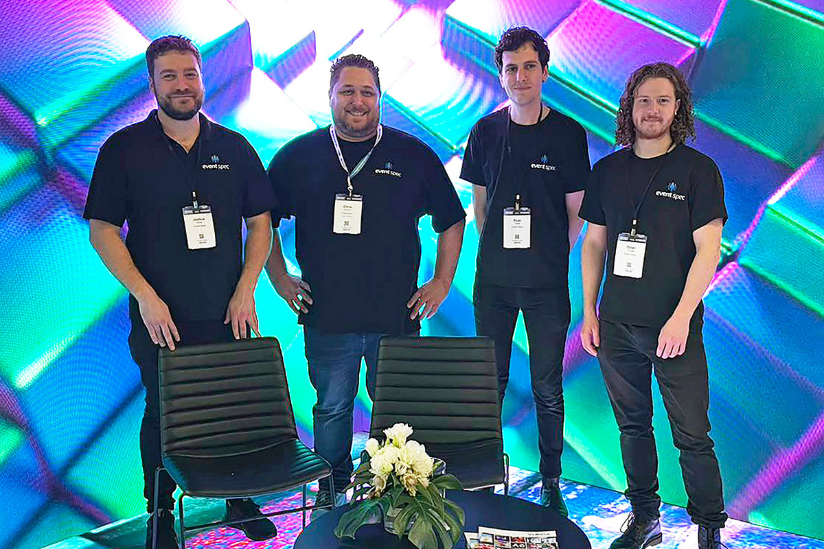 Four team members posing in front of a colourful neon video wall.