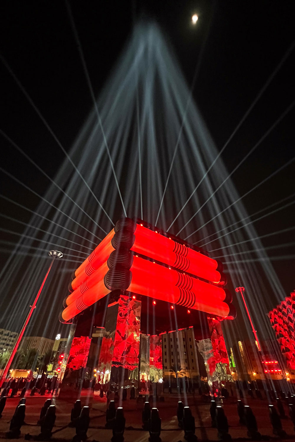 White beams converging above a red agal-inspired installation for Saudi Founding Day.