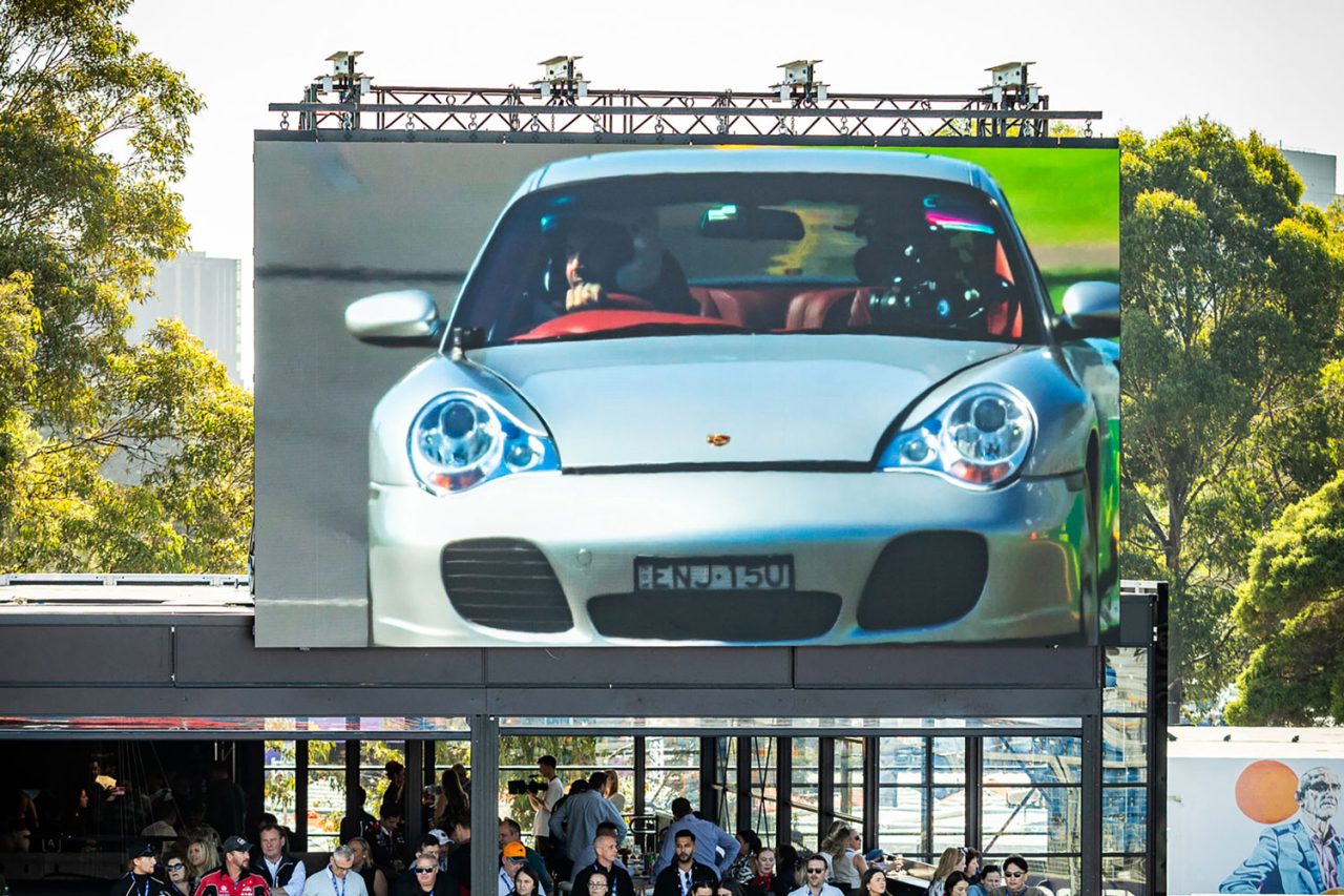 Car footage on a large outdoor screen at the 2024 Australian Grand Prix.