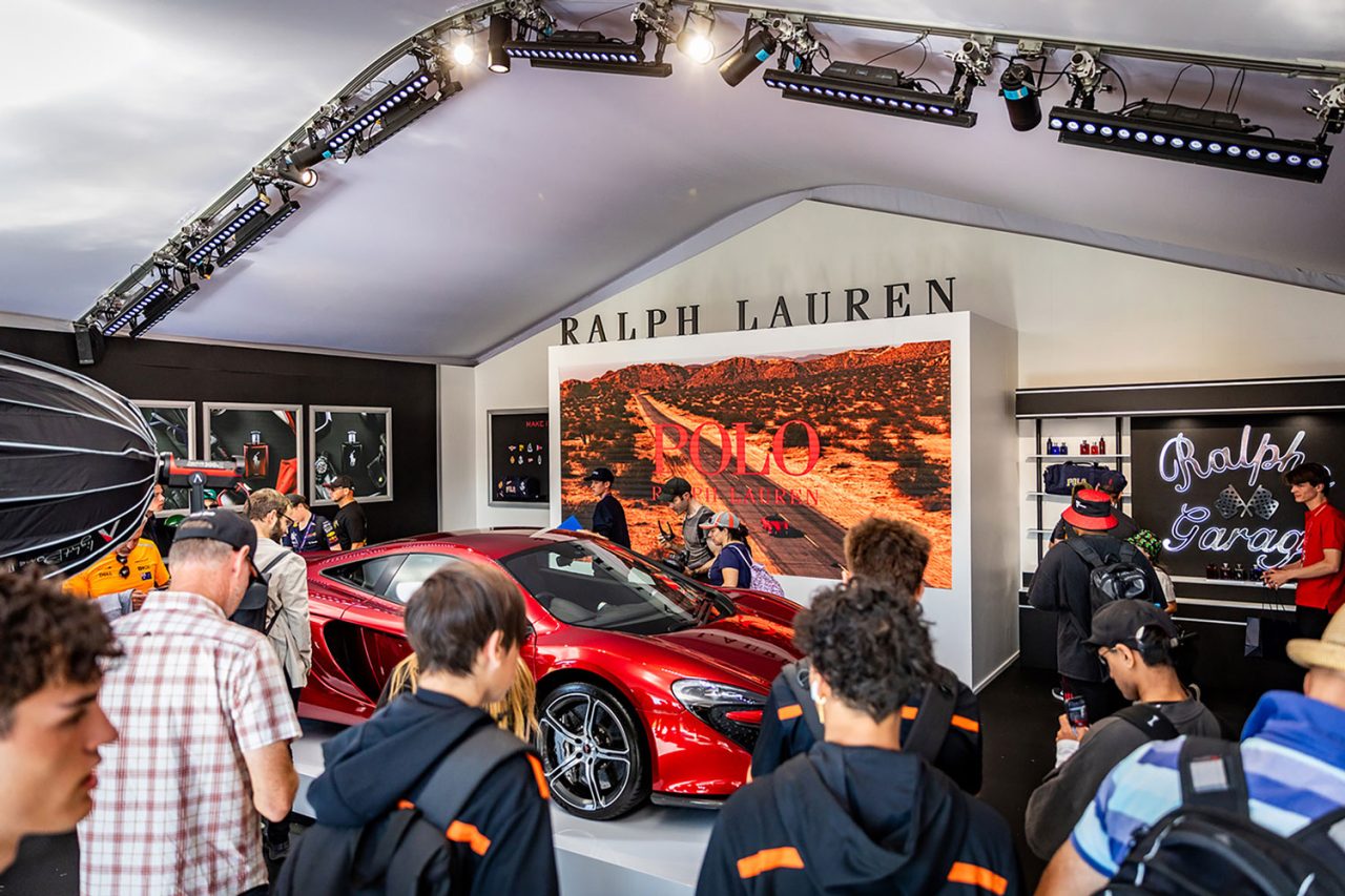 Visitors around a display car and digital advertising in an Australian Grand Prix sponsor lounge.