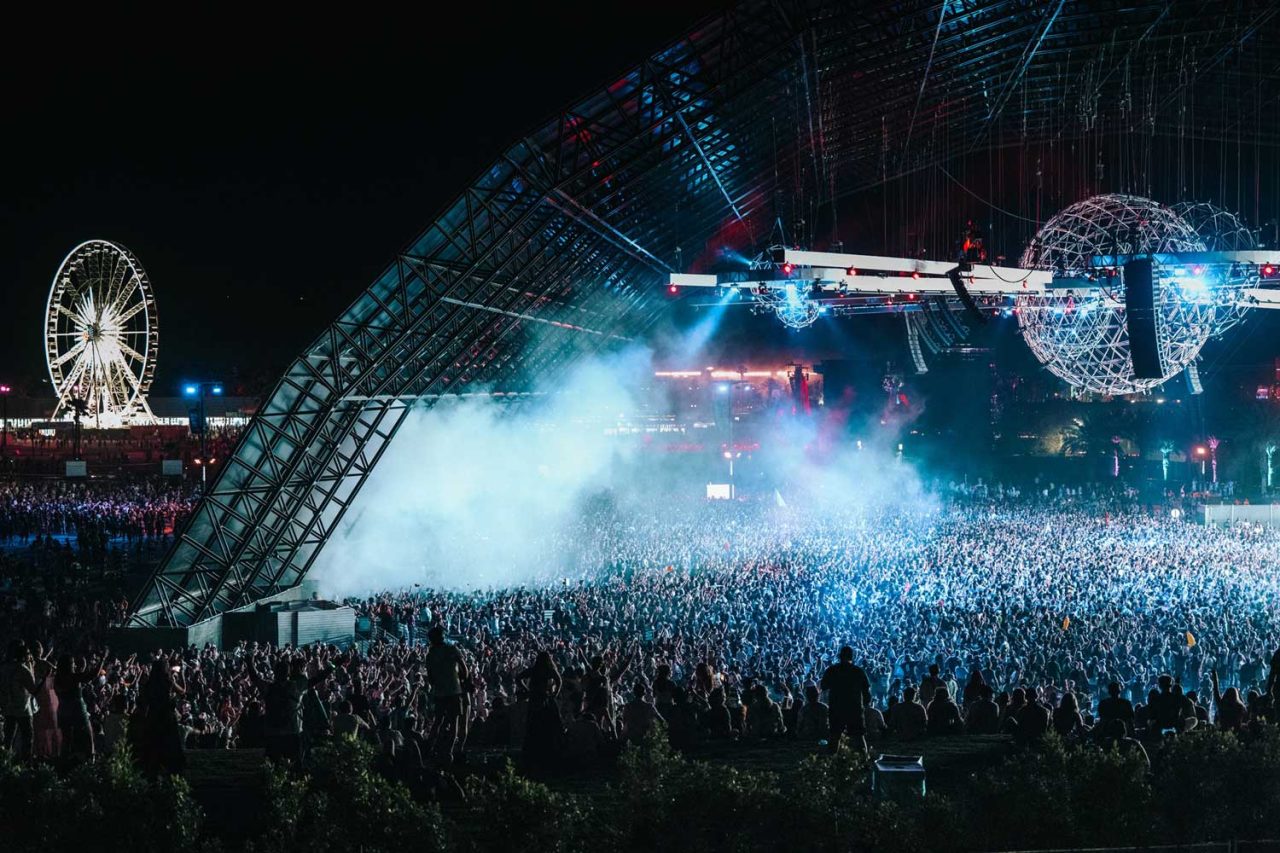 Crowd beneath the illuminated Sahara Tent at Coachella 2024.