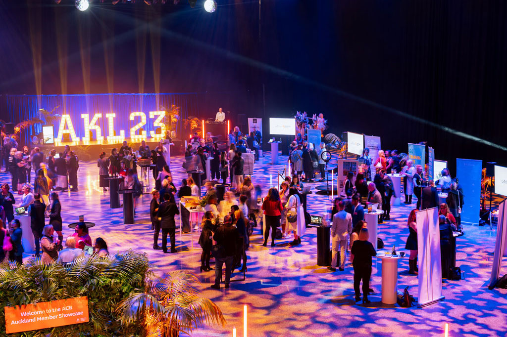 Guests at the AKL23 showcase amid colourful lighting in the Viaduct Events Centre.