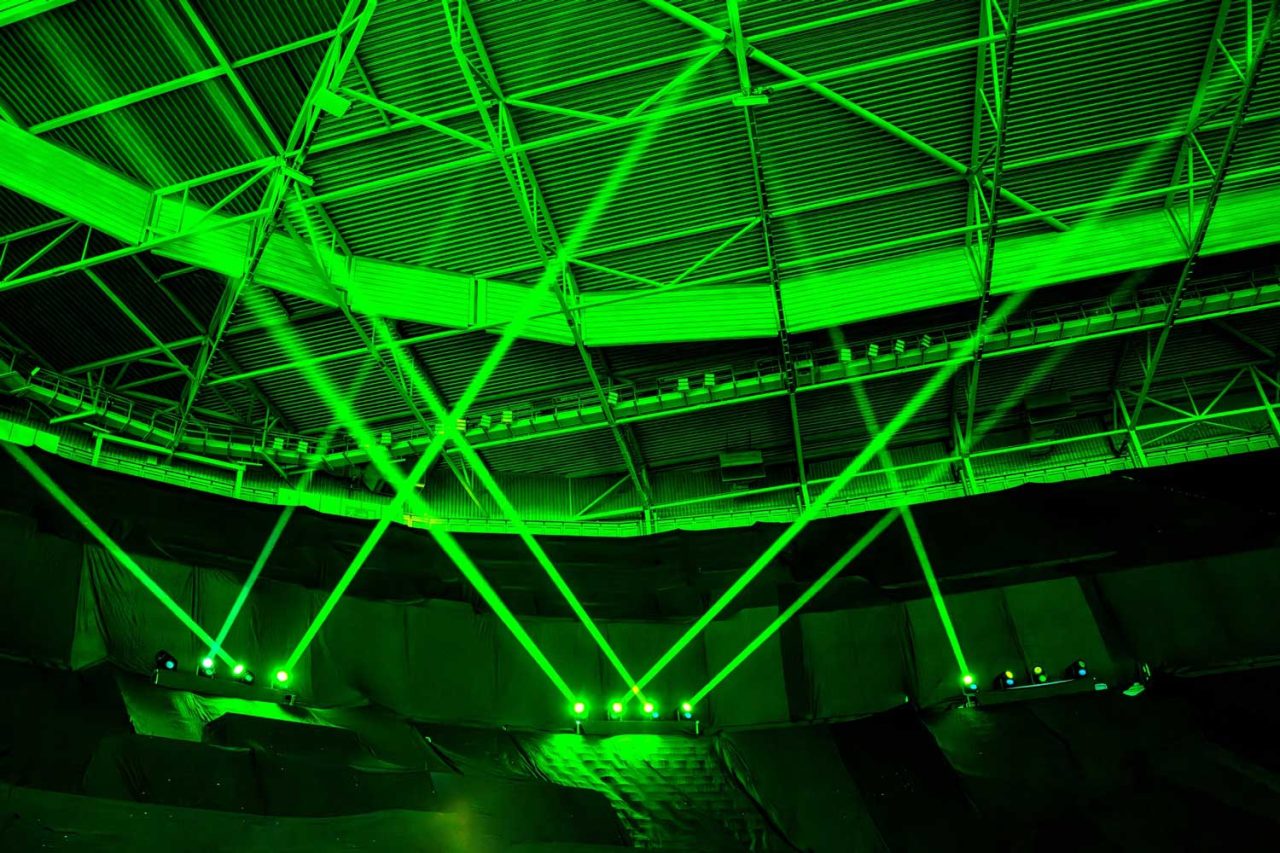 Green beams crisscrossing the stadium roof on the Music of the Spheres tour.