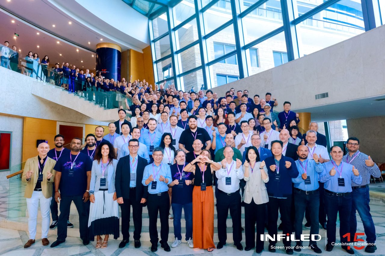 Large group of INFiLED anniversary guests posing on an indoor staircase.