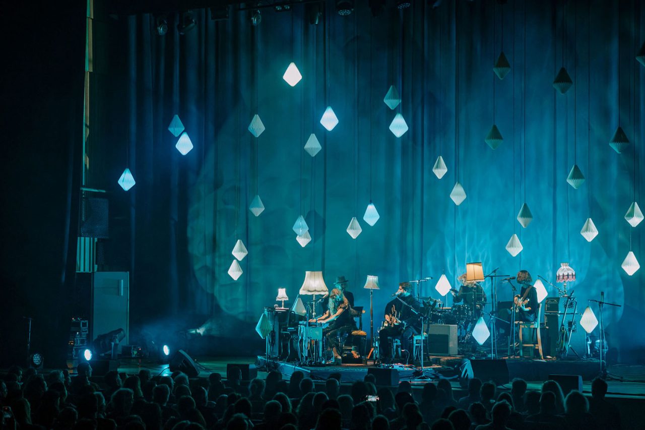 Blue-lit stage decorated with suspended lamps on the Living Room Sessions tour.