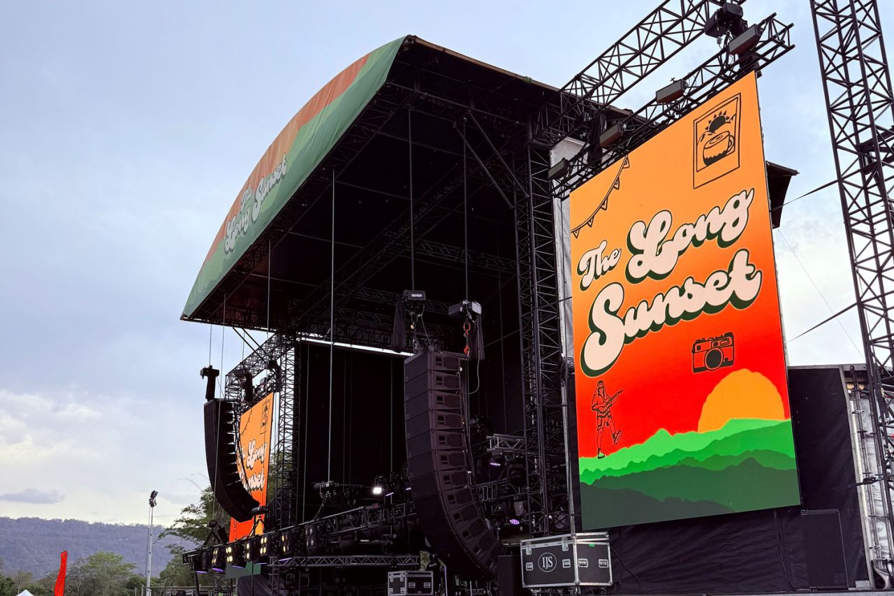 Side view of The Long Sunset festival stage with a tall branded LED screen.