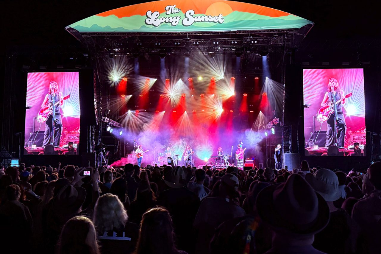 Red stage lighting and live video screens above the crowd at The Long Sunset at night.
