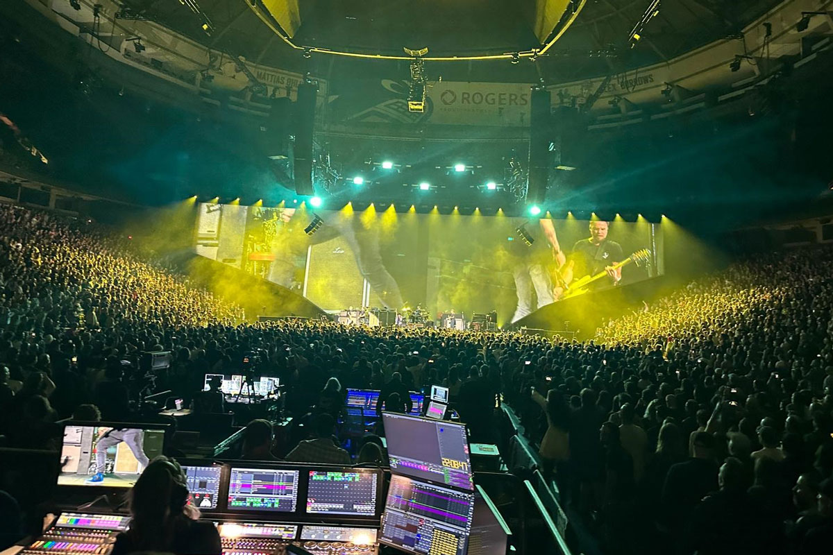 Arena crowd facing a wide stage bathed in yellow light on Pearl Jam's Dark Matter tour.