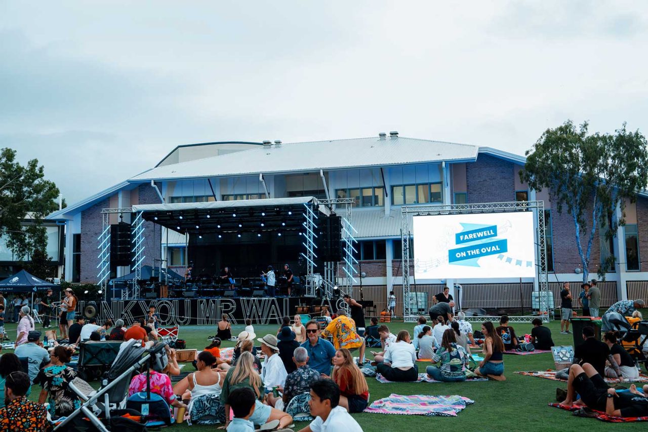 Guests seated on the lawn before the stage and screen at All Saints Anglican School.