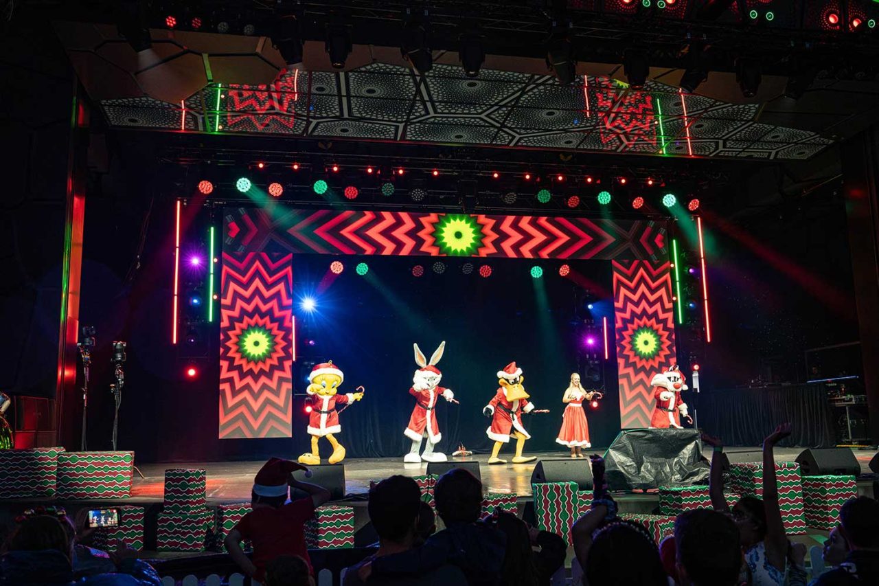 Costumed performers against a colourful video backdrop at the 2024 Gold Coast Mayor's Carols.
