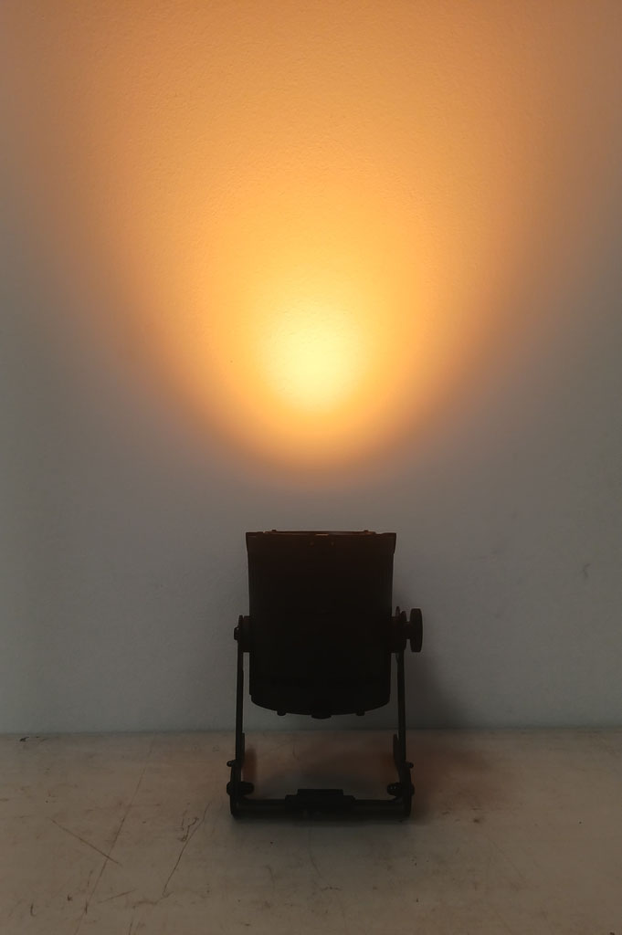 Astera QuikSpot casting an amber wash onto a white wall.