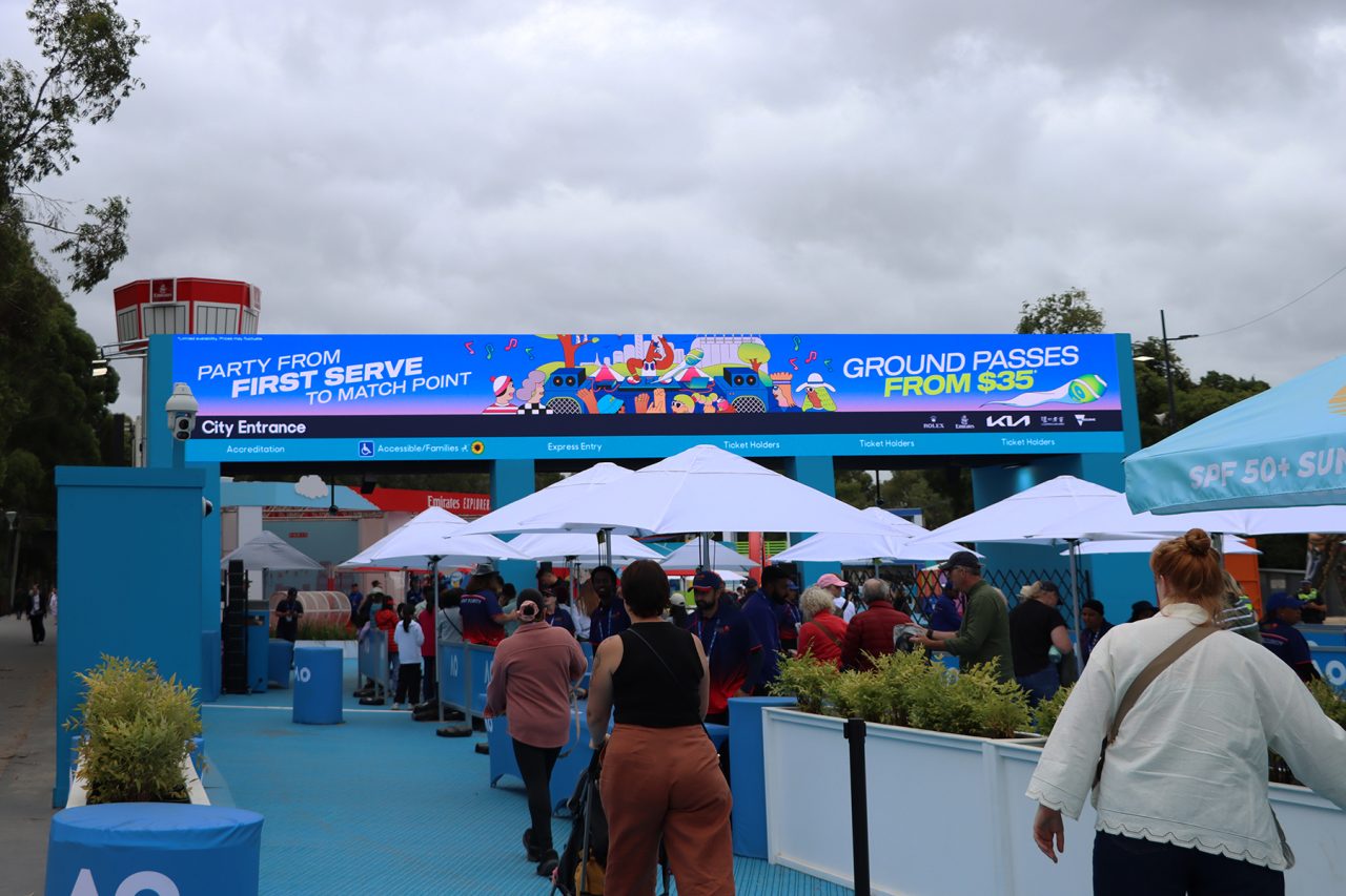 Visitors pass beneath a wide digital entry banner at the 2025 Australian Open.