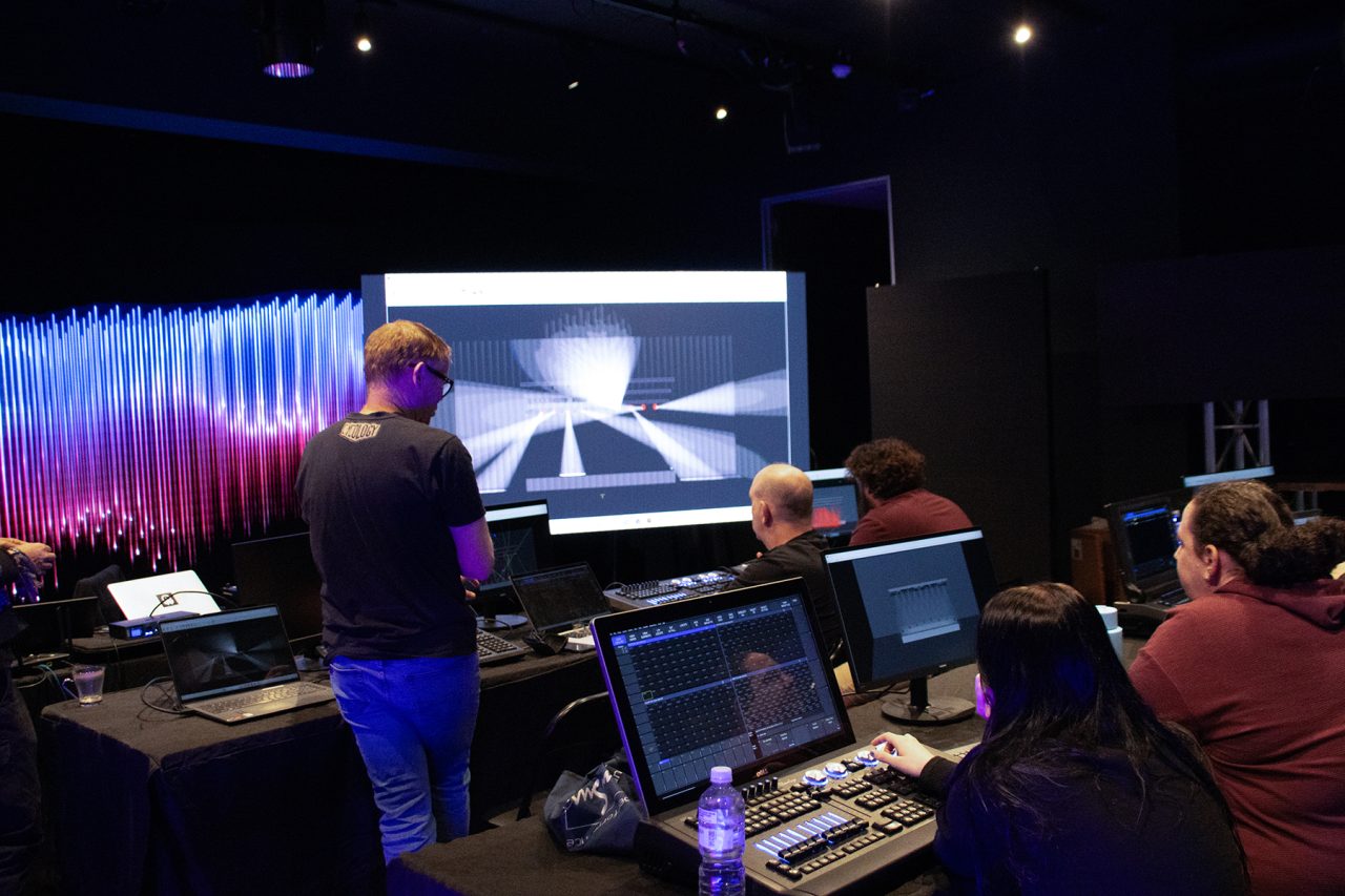 Trainer demonstrating lighting software on a large screen to seated participants.