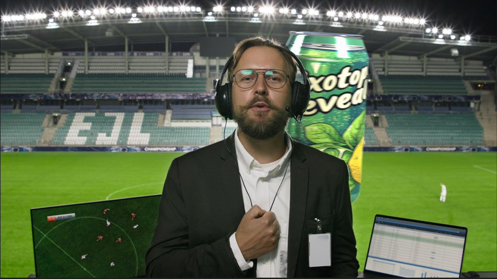 Presenter wearing a headset beside a sports field during a Pixotope broadcast demonstration.