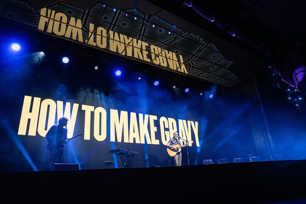 How to Make Gravy graphics on HOTA's stage screen beneath blue lighting.