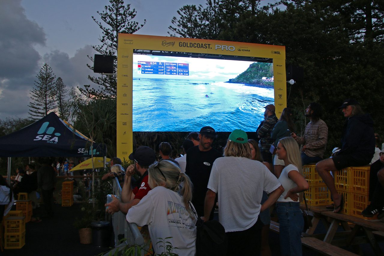 A yellow-framed screen showing surf coverage above the crowd at the Gold Coast Pro.