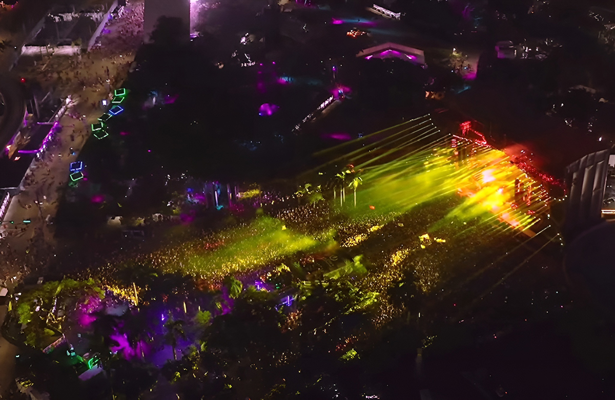 Aerial view of the Ultra Miami crowd and stages lit in yellow and purple.