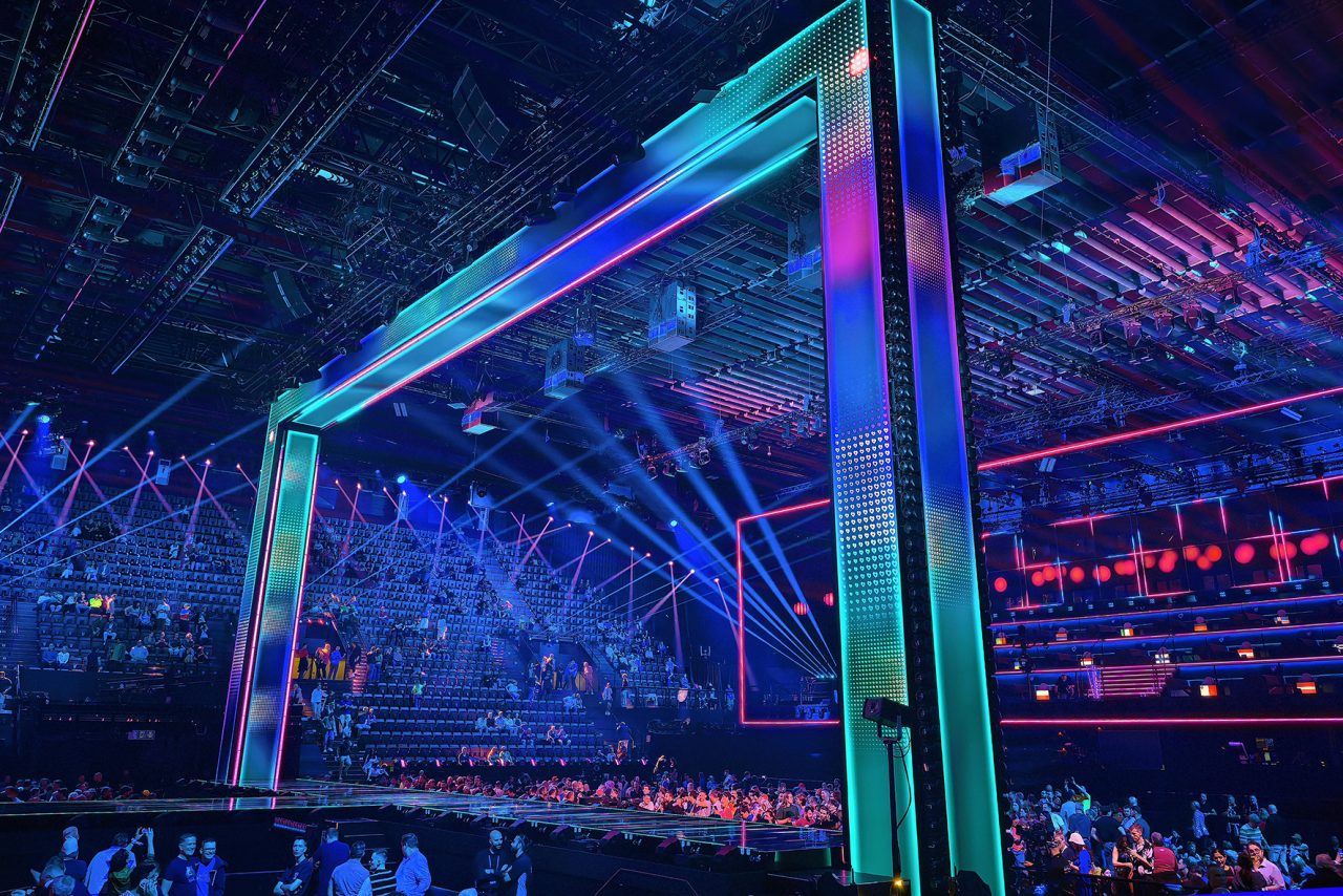 Low view of a giant rectangular frame outlined in turquoise and purple light.
