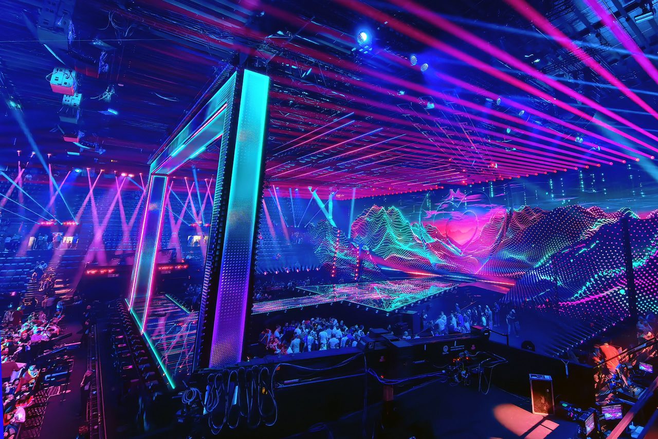 Large rectangular stage frame surrounded by magenta and turquoise beams at Eurovision 2025.
