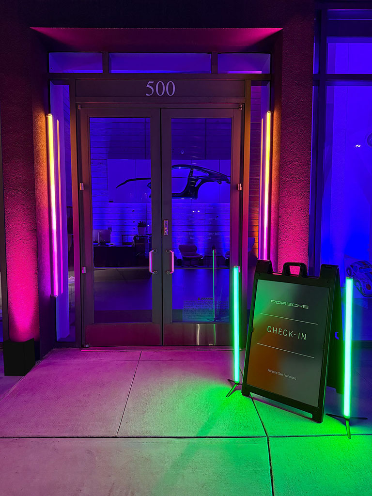 Showroom entrance framed by pink, blue and green lighting for the Porsche reveal.