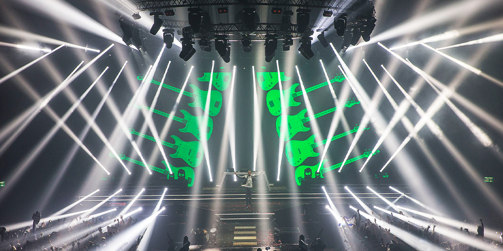 Crossing white beams around a green stage backdrop.
