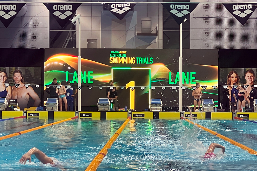 Swimmers race towards the large digital backdrop at the 2025 Australian Swimming Trials.