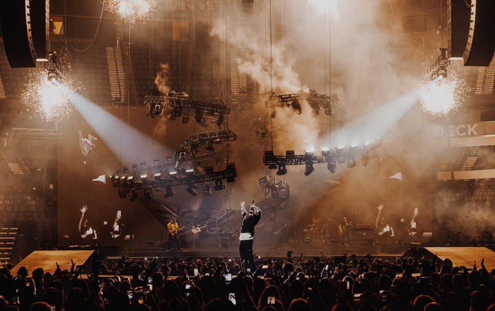 Moving lighting rig amid warm stage haze on Kane Brown's High Road tour.