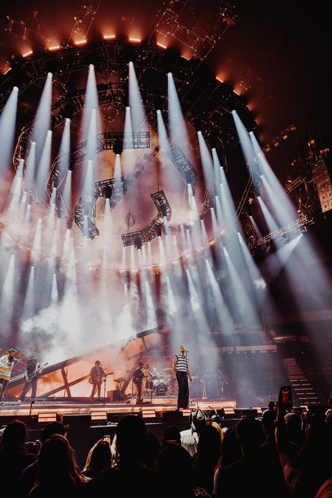 Vertical white beams surrounding performers on the High Road tour stage.