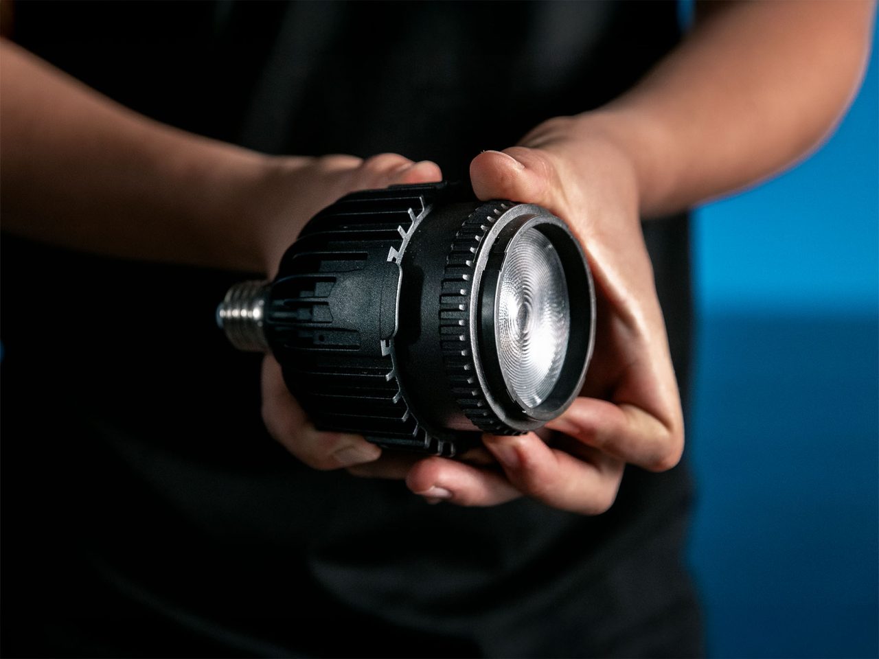 Person holding an Astera SolaBulb to show its lens and ribbed housing.