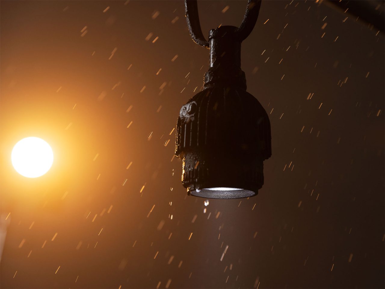 Hanging Astera SolaBulb with raindrops visible in warm backlight.