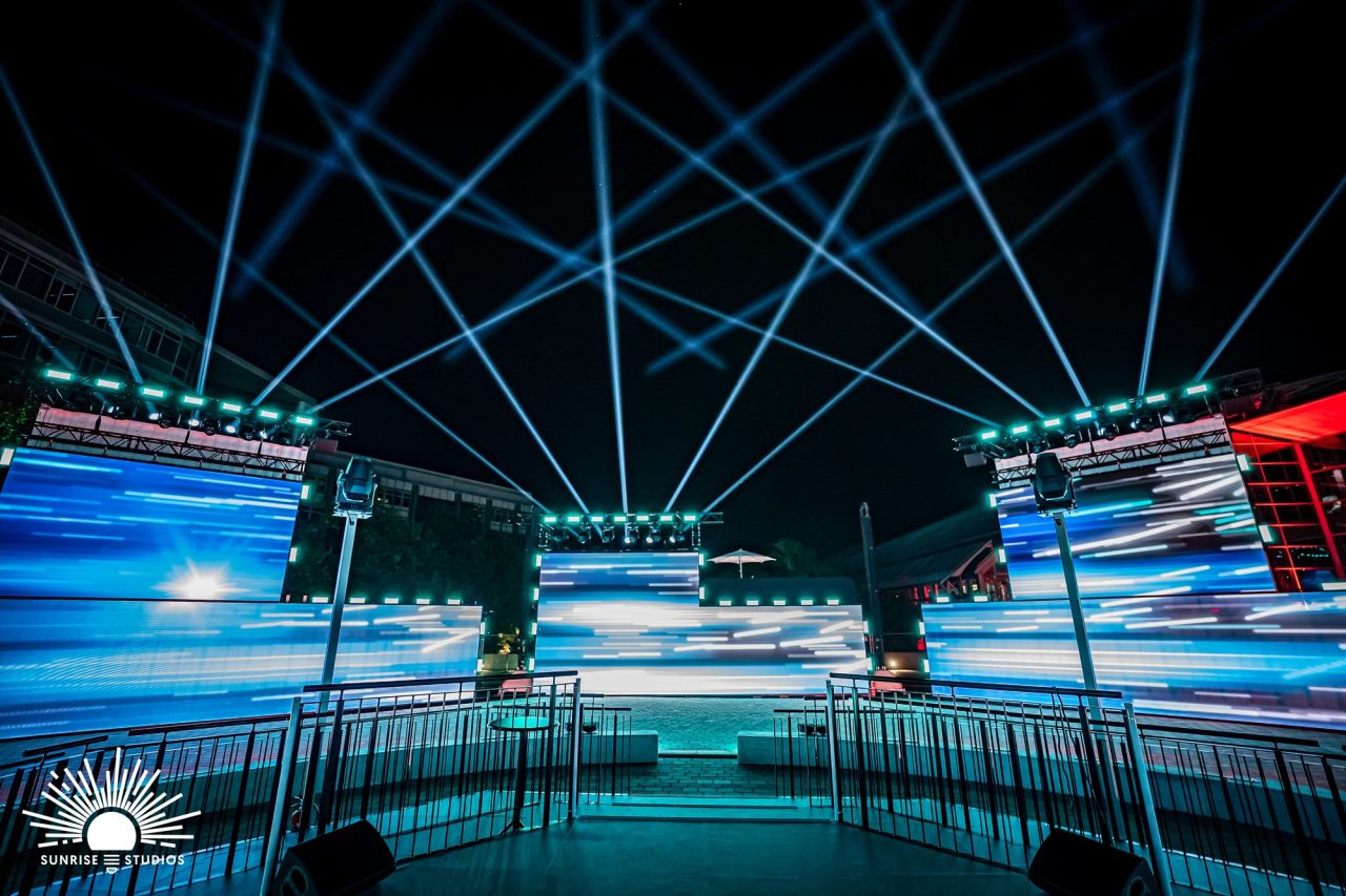 Panoramic blue screen graphics and overhead beams surrounding the Audi Q3 launch stage.
