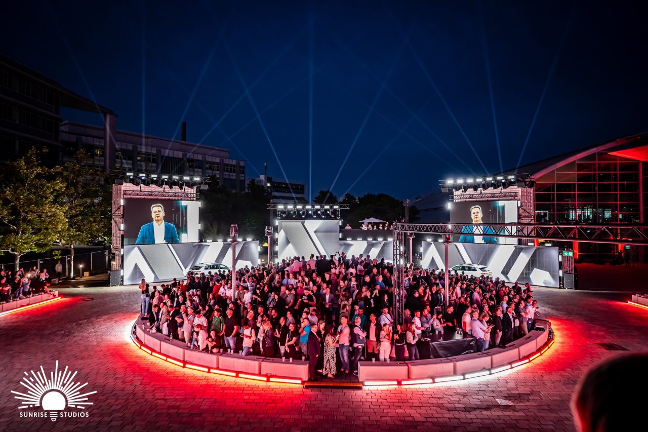 Guests seated around a circular red-lit stage for the Audi Q3 launch.