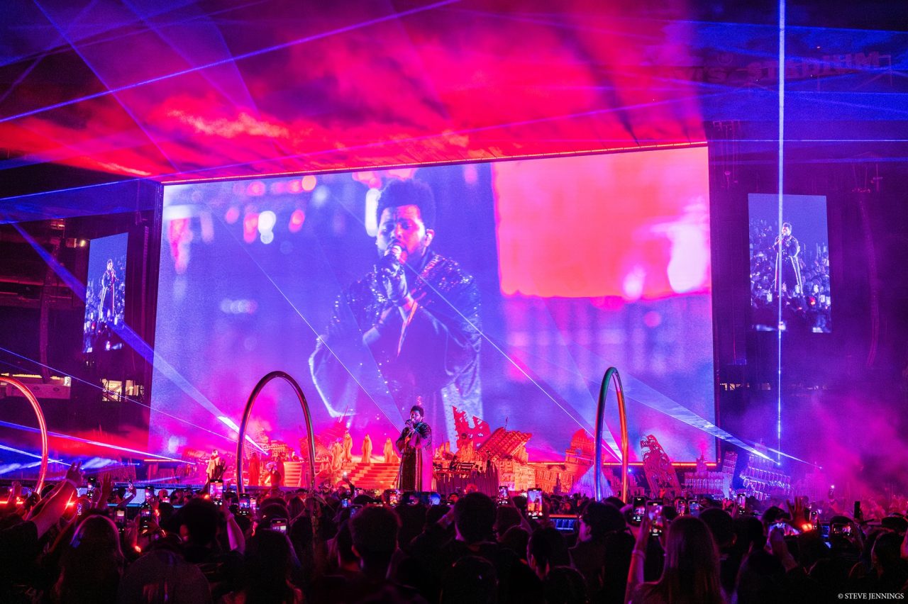 Red and purple screens behind curved stage structures on The Weeknd's tour.