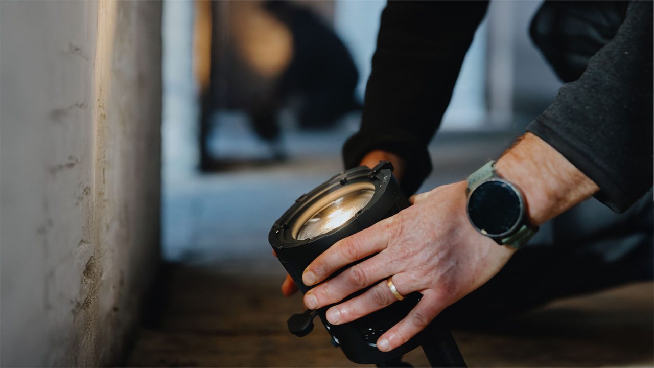 Hands positioning a QuikBeam fixture beside a wall.