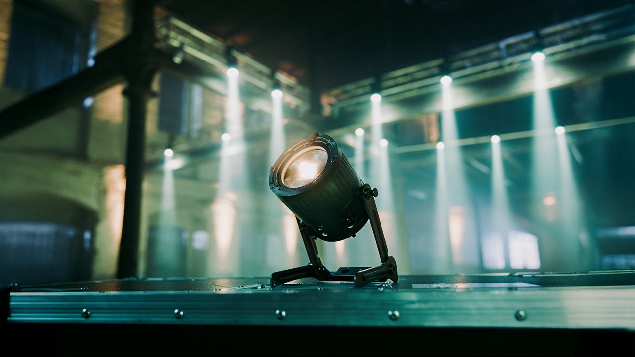QuikBeam fixture on the floor with white beams filling an industrial room behind.