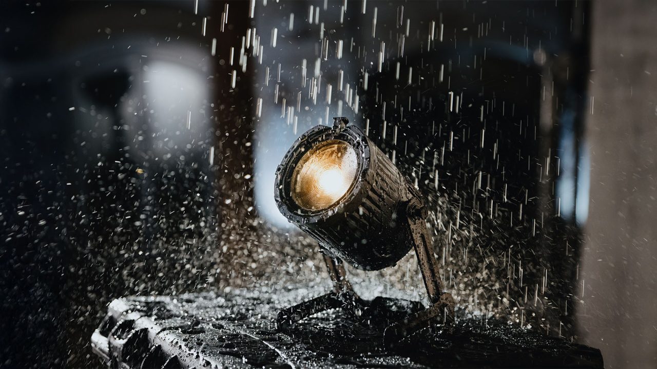 Astera QuikBeam emitting warm light while water falls over it.