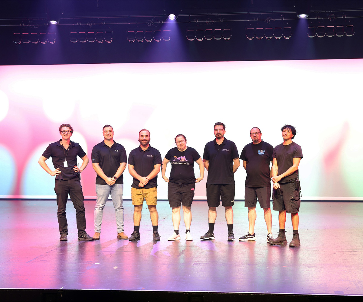 Seven team members on HOTA's theatre stage after the lighting upgrade.