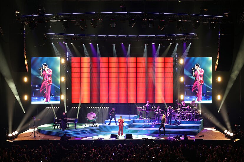 Orange vertical graphics across the tour's central video wall between two live screens.