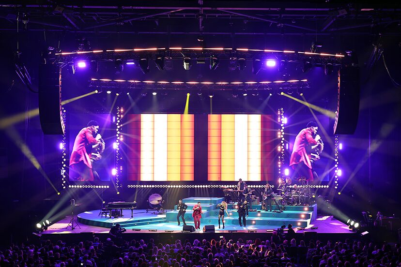 Purple arena lighting around the stage and orange video columns on the 100 Times Around the Sun tour.