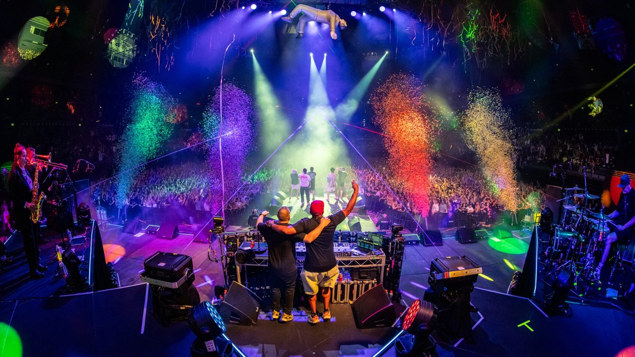 Colourful confetti fills the stage beneath blue and green lighting at the Hilltop Hoods show.