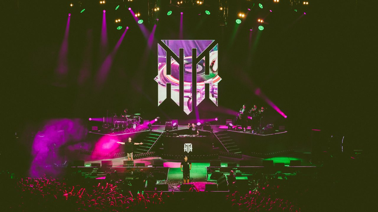 Green and purple lighting around the Hilltop Hoods emblem on the Never Coming Home tour.