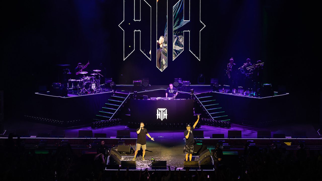 Wide view of the purple-lit Hilltop Hoods stage, emblem and performers.