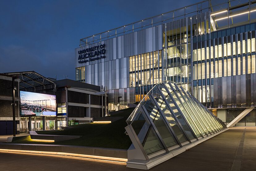 Hiwa Recreation and Wellbeing Centre illuminated at dusk, with a glass entrance structure in the foreground.